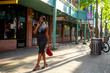 African american young black female fashion model is walking along Chinatown square in Chicago wearing a beautiful trendy stylish black dress. The summer lifestyle this tourist leads in city is fun