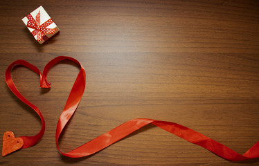 Valentine's Day, February 14th. Red and white heart on a wooden background. With candles and a red silk ribbon.