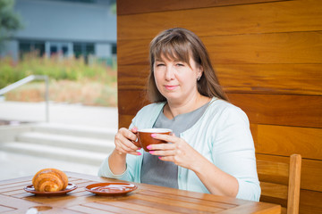 Young Caucasian woman with straight hair drinking tea in a coffee shop