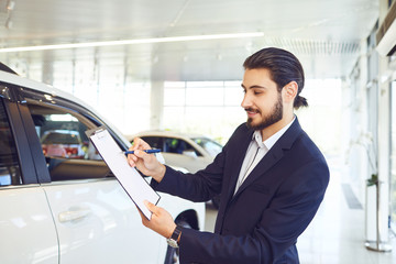 Canvas Print - A car dealer is holding documents on the sale of a car.