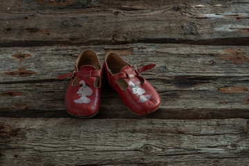  Old children's shoes are on a wooden background.