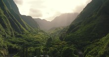 4k Aerial Drone Pan Up Over Lush Green Valley In Hawaiian Rainforest With Sun Rays.