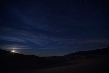 Moon Sets Below Sand Dunes and Star Field