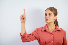 Woman Touching An Imaginary Screen With Her Finger.Portrait Of Female College Student Touching Something On Copy Space.Attractive Young Woman Touching A Virtual Interface With Her Finger