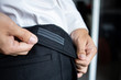 A man's hand is holding the edge of an elastic belt. Black trousers for men that can be stretched.