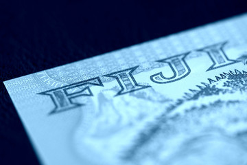 Wall Mural - Five Fijian dollars banknote on a dark background close up. Money background blue color toned