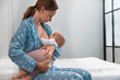 © New Africa - Young woman breast feeding her little baby in bedroom