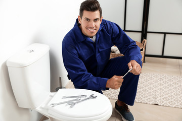 Canvas Print - Professional plumber working with toilet bowl in bathroom