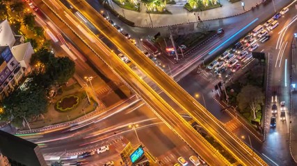 Wall Mural - Timelapse of night city traffic on 4-way stop street intersection in bangkok at night, thailand. 4K UHD horizontal aerial view.