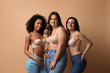 © New Africa - Group of women with different body types in jeans and underwear on beige background