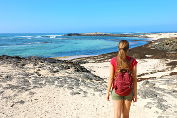 Wall Mural - Female hiker backpacker enjoying view of amazing wild beach in Fuerteventura, Canary Islands