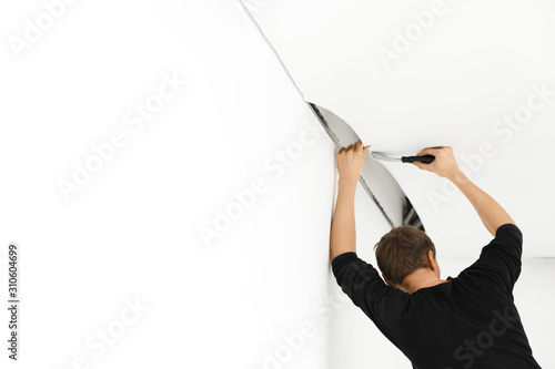 Fotografía Repairman installing white stretch ceiling in room