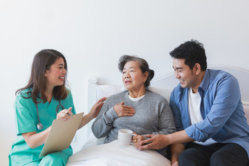 Asian Senior old woman on the bed with doctor and her son in hospital