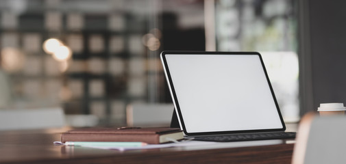 Cropped shot of modern office room with blank screen tablet and office supplies