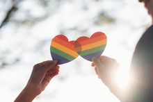 Close Up Hand Of LGBTQ Couple Holding Rainbow Heart.
