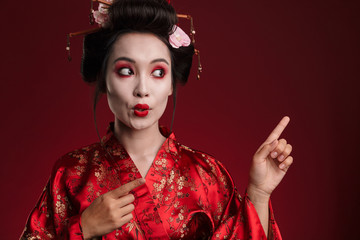 Poster - Image of geisha woman in japanese kimono pointing finger at copyspace