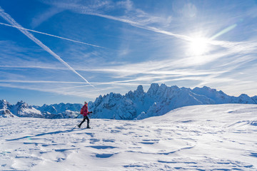 active senior woman snowshoeing under the famous Three Peaks from Prato Piazzo up to the Monte Specie in the three oeaks Dolomites area near village of Innichen, South Tyrol, Italy