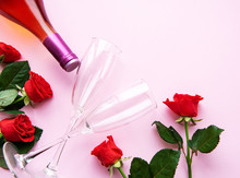 Valentines Day Greeting Card. Red Roses, Wine And Glasses For Wine On A Light Pink Background. Flat Lay, Top View, Copy Space
