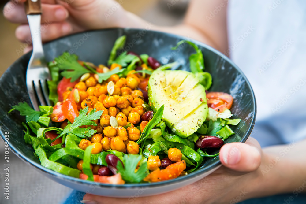 Clean eating, vegan healthy salad bowl closeup , woman holding salad bowl, plant based healthy diet with greens, chickpeas and vegetables - obrazy, fototapety, plakaty 