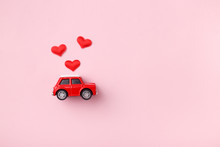 Red Retro Toy Red Car With Red Bow For Valentine's Day On Pink Background With Heart Confetti. Top View, Flat Lay