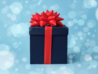 square blue cardboard box for a gift and silk red bow on a blue background