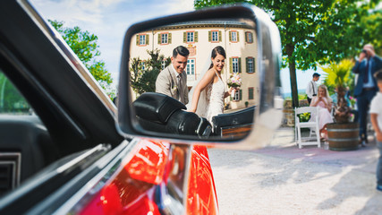 Wall Mural - beautiful bride and groom in the mirror of the bride's car