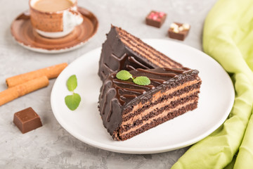 Homemade chocolate cake with milk cream and a cup of coffee on a gray concrete background. side view, selective focus.