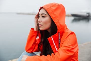 Sticker - Smiling attractive young asian woman wearing raincoat