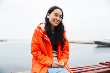 Sticker - Smiling attractive young asian woman wearing raincoat