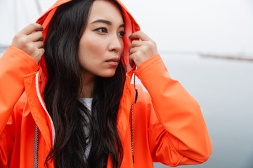 Attractive young asian woman wearing raincoat walking outdoors