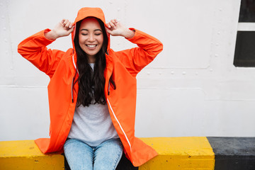 Sticker - Attractive smiling young asian woman wearing raincoat