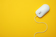 Wired computer mouse on yellow background, top view. Space for text