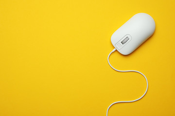 wired computer mouse on yellow background, top view. space for text