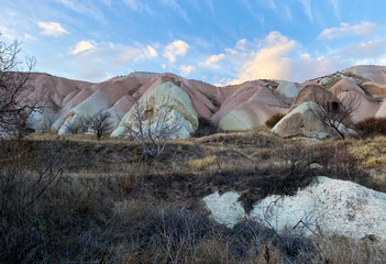 Wall Mural - View of a valley filled with ancient rock formations. Blue sky, white clouds. Landscape. Cappadocia, Turkey November 5, 2019.