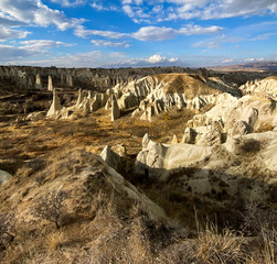 Wall Mural - View of a valley filled with ancient rock formations. Blue sky, white clouds. Landscape. Cappadocia, Turkey. 5 november 2019