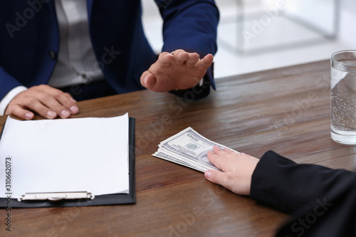 Fotografía Businessman refuses to take bribe money at wooden table, closeup