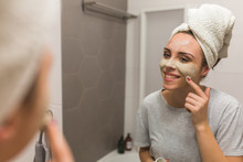 Woman Applying Cosmetic Face Mask In Her Bathroom