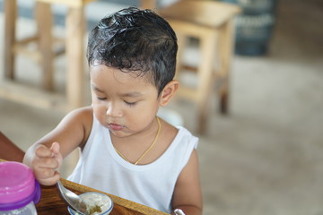 Wall Mural - Little cute boy with very long eyelashes. Baby boy Wearing a white sleeveless shirt. can use for background concept. Happy kid eating drinking concept.