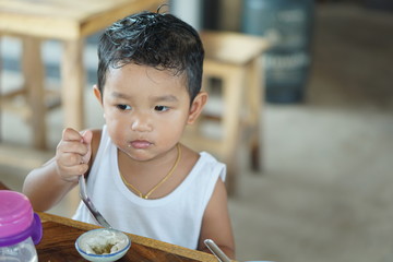 Wall Mural - Little cute boy with very long eyelashes. Baby boy Wearing a white sleeveless shirt. can use for background concept. Happy kid eating drinking concept.