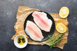 Fillet of fish on a kitchen board. Healthy food ingredients. Fresh sea fish fillet, lemons, spices, salt, herbs, spices for a comfortable diet. Against a dark background. Top view.