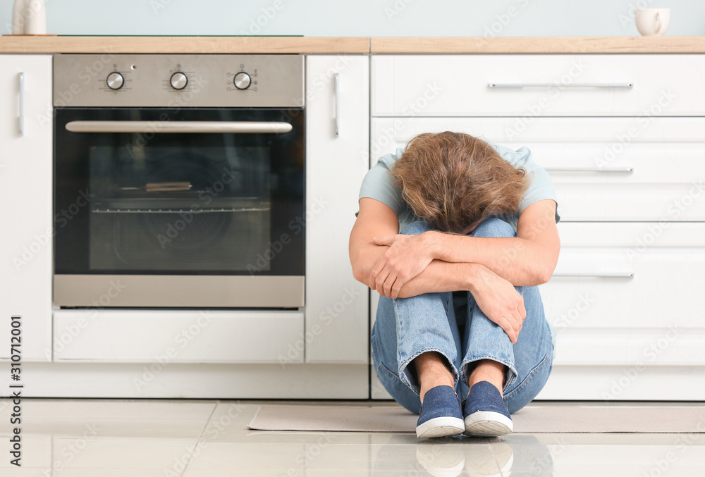 Depressed man in kitchen at home