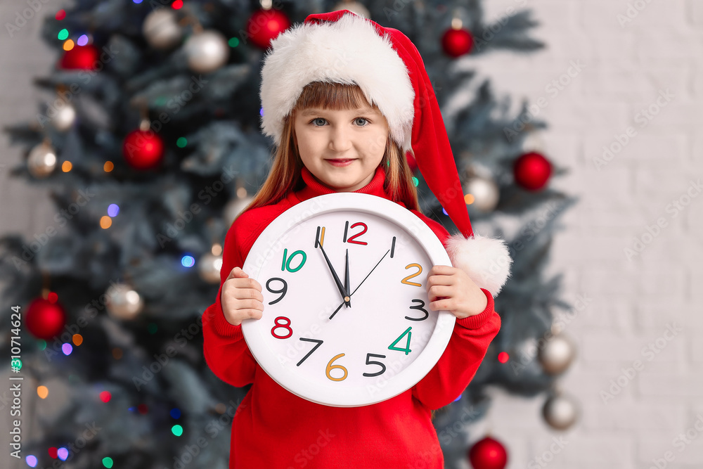Little girl in Santa hat and with clock at home. Christmas countdown concept