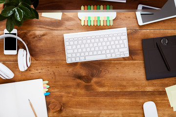 Modern table with open empty blank notebook organizer with pen for planning work and computer monitor on desk with devices stationery supplies keyboard on brown wooden office desk, above top view