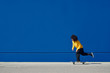 © guille Faingold/Stocksy - Ethnic skater riding alongside blue wall