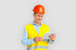© Viktoriia - Construction. Mature man in hardhat and uniform standing isolated on white watching video on digital tablet smiling cheerful