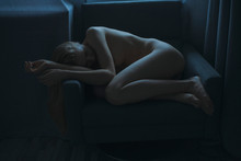 Woman Lying Naked In An Armchair In The Dark