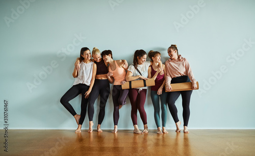 Fotomural Laughing young friends standing in a gym after yoga class