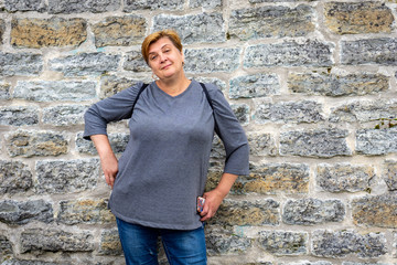 A Mature plump woman walks in an ancient castle, smiles and looks at the camera.