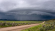 Shelf cloud storm moving over the landscape with road leading of into the distance towards the storm.
