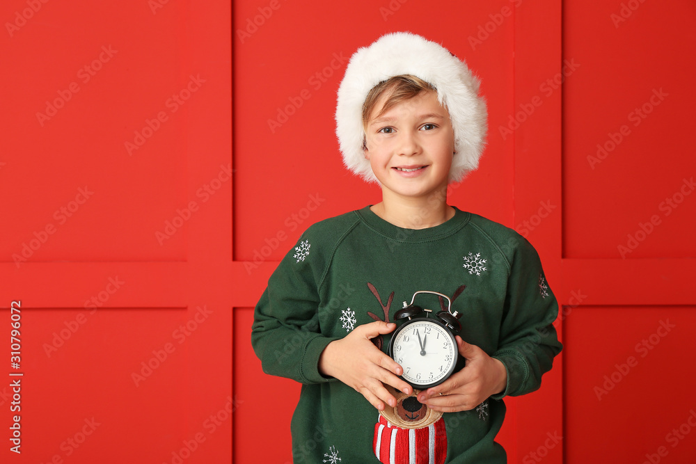 Little boy with alarm clock on color background. Christmas countdown concept